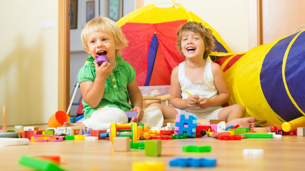 Dos niñas alegres jugando con bloques en el interior de una casa
